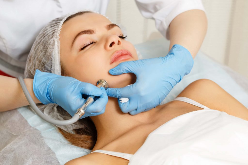 doctor performing dermabrasion treatment on women’s cheek
